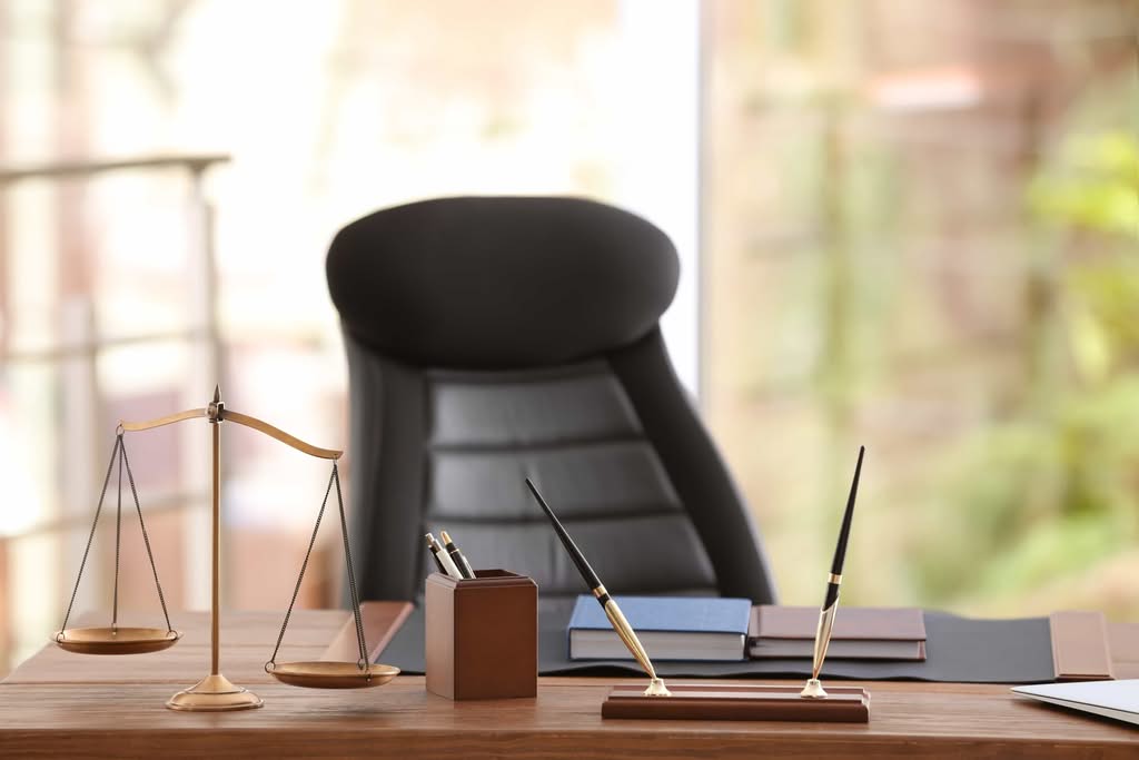 A professional law office desk featuring a gold scale of justice, pens, and books, symbolizing legal services in Central Florida attorneys conduct depositions.