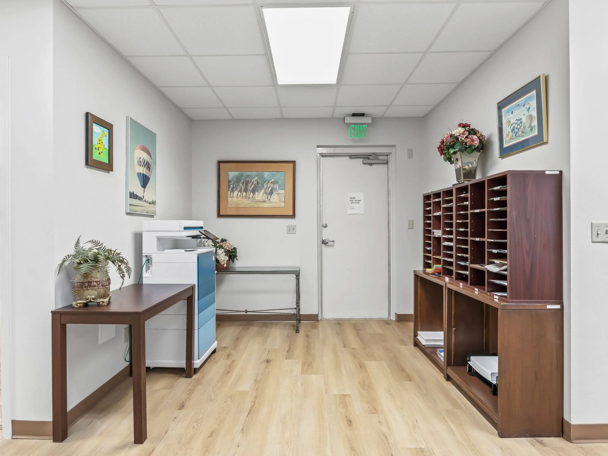 An office workroom and mail room with mail sorting cubbies, copy machine, and side tables in a professional office suite in Ocala, FL.