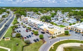 Aerial view of a shopping center featuring multiple parking lots and surrounding green spaces.
