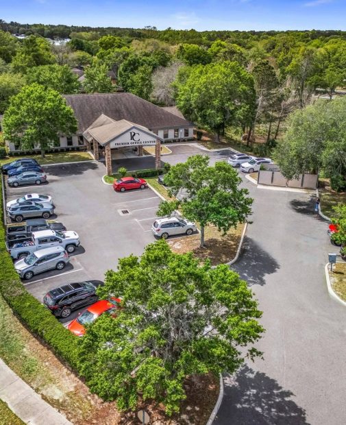 Aerial drone view of Premier Office Center showing office building amenities including ample parking, covered portico, and lush landscaping in Ocala, FL.