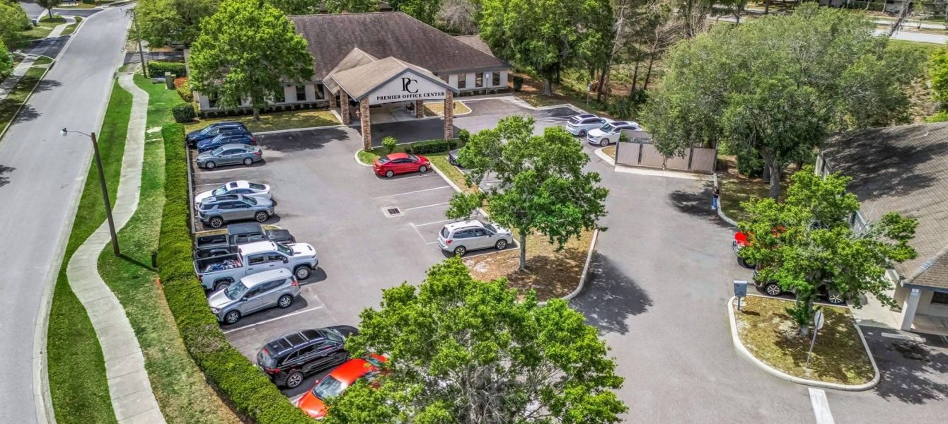 Aerial drone view of Premier Office Center showing office building amenities including ample parking, covered portico, and lush landscaping in Ocala, FL.