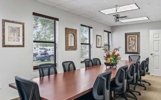 Spacious conference room with a long wood table, ergonomic chairs, and ceiling projector in professional office suites in Mount Dora, FL.