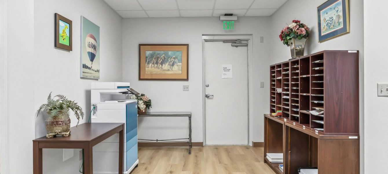 An office workroom and mail room with mail sorting cubbies, copy machine, and side tables in a professional office suite in Ocala, FL.