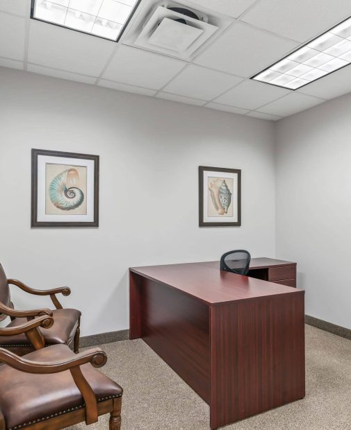 A private office space featuring a mahogany desk, desk chair, and guest seating in a professional office suite setting in The Villages, FL.