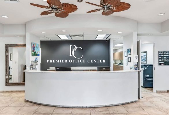 Modern reception lobby at Premier Office Center featuring a white curved front desk and logo sign for professional office suites in Wildwood, FL.